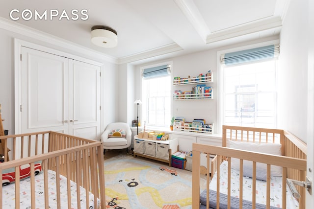 bedroom featuring a closet, a crib, and ornamental molding