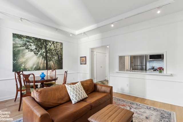 living room with baseboards, wood finished floors, and rail lighting