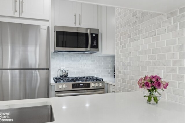 kitchen featuring decorative backsplash, appliances with stainless steel finishes, white cabinets, and light countertops