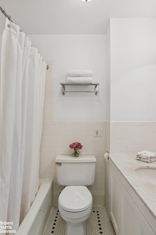 bathroom with tile patterned floors, toilet, tile walls, wainscoting, and vanity