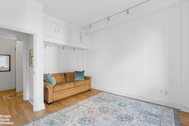 living area with track lighting, light wood-style floors, and baseboards