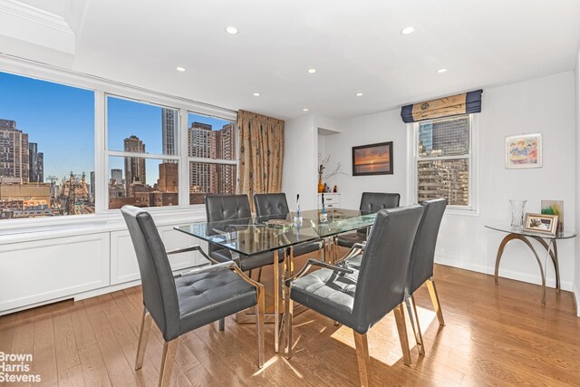 dining space featuring light wood finished floors, recessed lighting, a wealth of natural light, and a city view