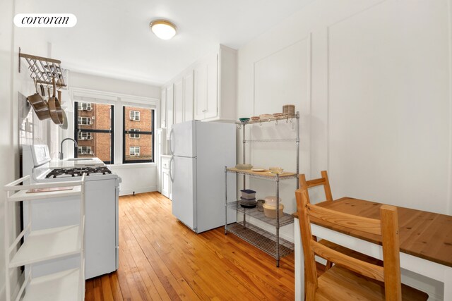 kitchen with white cabinetry, white appliances, and light hardwood / wood-style floors