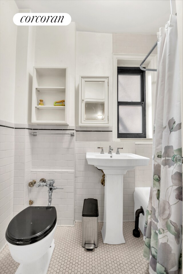 bathroom with tile walls, tile patterned floors, and toilet