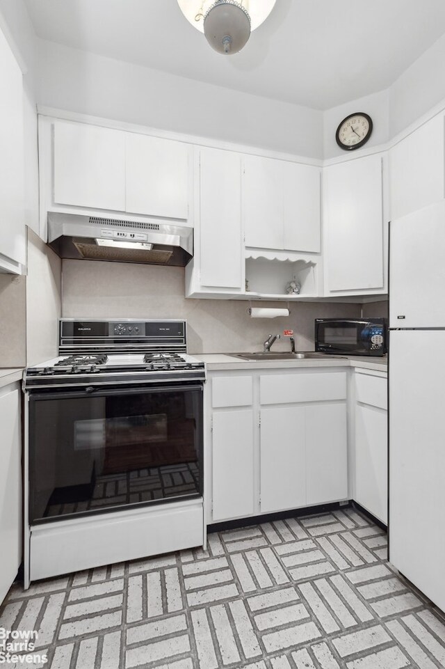 kitchen with white refrigerator, sink, white cabinets, and range with gas stovetop