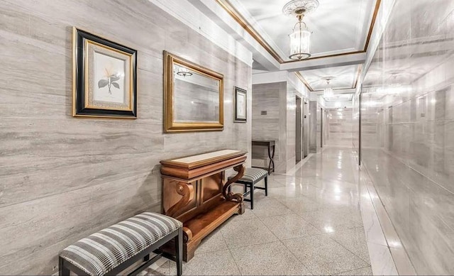 hallway featuring ornamental molding, a chandelier, and granite floors