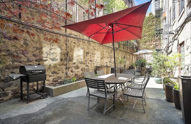view of patio featuring outdoor dining area, grilling area, and fence