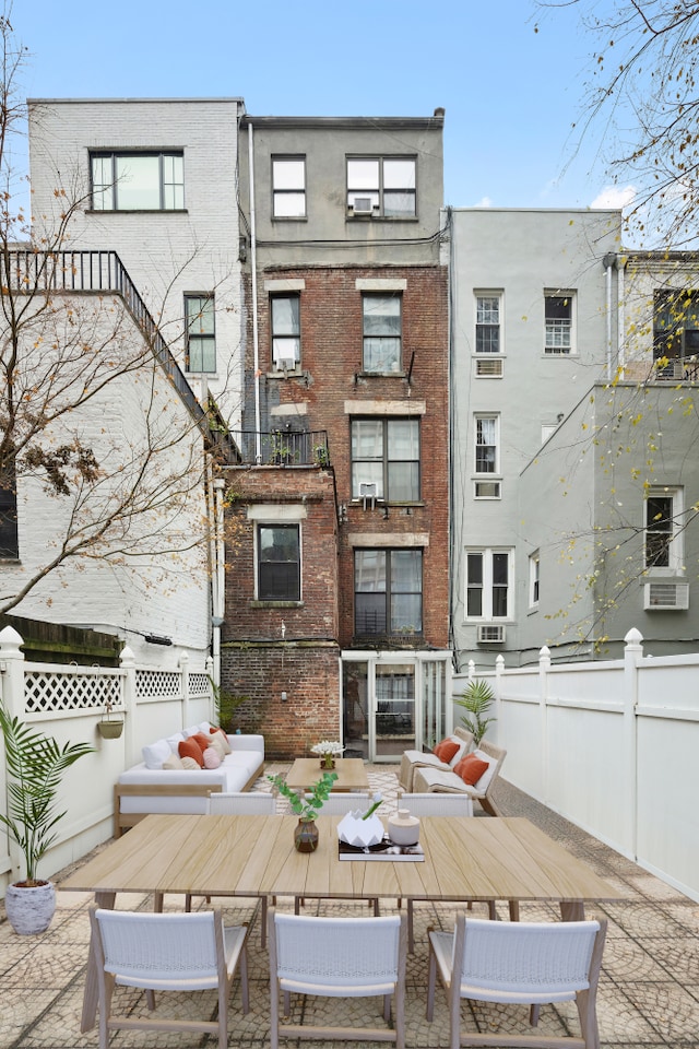 back of house featuring brick siding, fence, and an outdoor living space