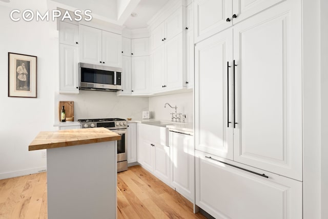 kitchen with a sink, white cabinetry, stainless steel appliances, and wooden counters