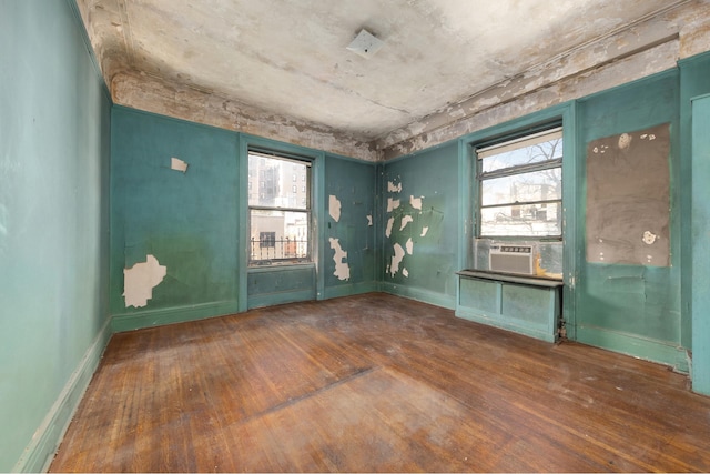 empty room with dark wood-style floors, plenty of natural light, and baseboards