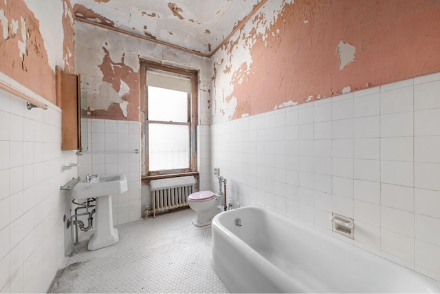 bathroom with a wainscoted wall, wallpapered walls, toilet, radiator heating unit, and a bath