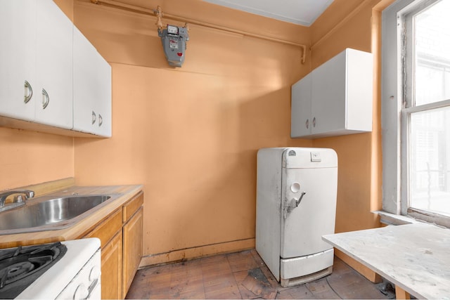 kitchen with white cabinets, light countertops, a sink, and light brown cabinets