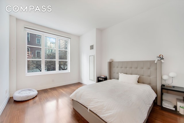 bedroom featuring wood finished floors, visible vents, and baseboards