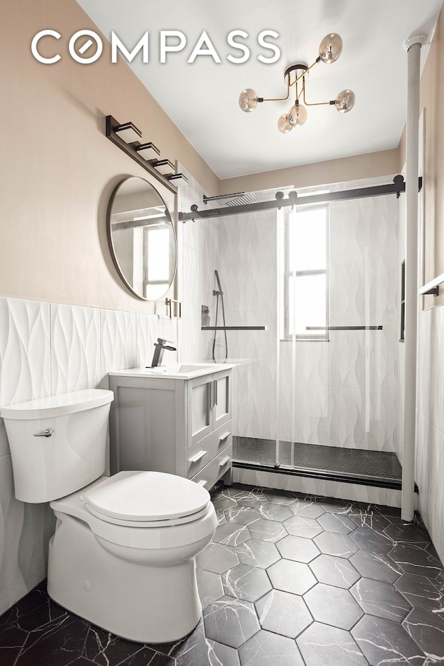 full bath with a baseboard heating unit, vanity, toilet, a stall shower, and wainscoting