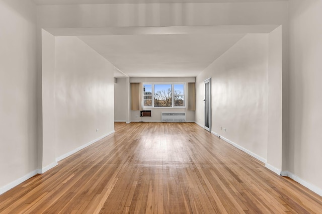 unfurnished living room with radiator heating unit and light hardwood / wood-style floors