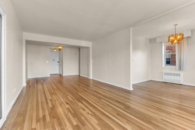 unfurnished living room featuring a notable chandelier, radiator heating unit, and light wood-type flooring