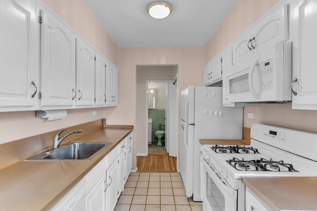 kitchen with white appliances, light tile patterned floors, sink, and white cabinets