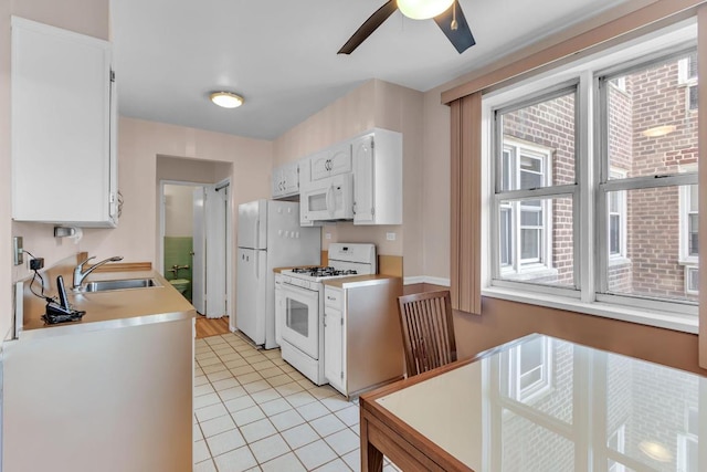 kitchen featuring white cabinetry, sink, light tile patterned floors, ceiling fan, and white appliances