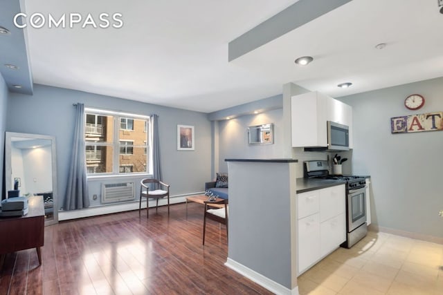 kitchen with white cabinetry, appliances with stainless steel finishes, a wall mounted air conditioner, and light hardwood / wood-style flooring