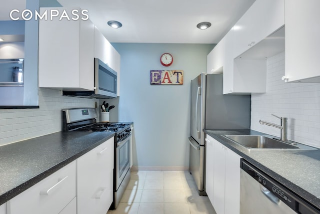 kitchen featuring light tile patterned floors, a sink, white cabinets, appliances with stainless steel finishes, and dark countertops