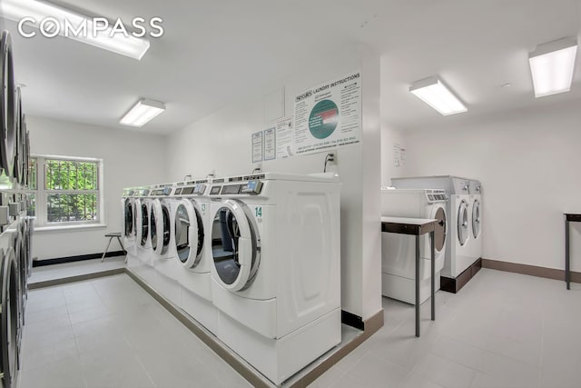 community laundry room featuring light tile patterned floors, washer and dryer, and baseboards