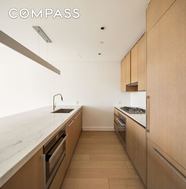 15 Hudson Yards Unit 37F, New York City, NY 10001 - kitchen with light wood finished floors, baseboards, light stone countertops, appliances with stainless steel finishes, and a sink