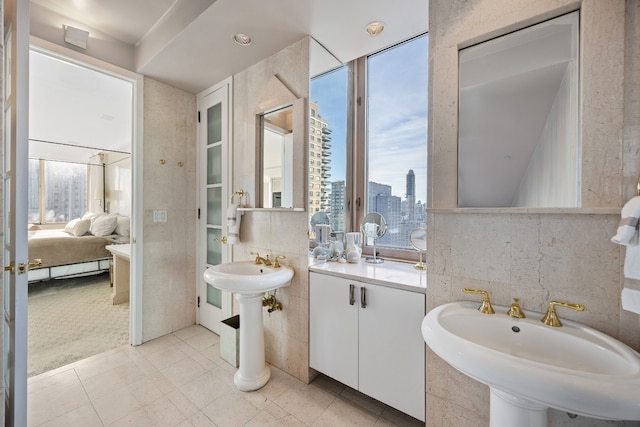 ensuite bathroom featuring plenty of natural light, two sinks, connected bathroom, and a city view