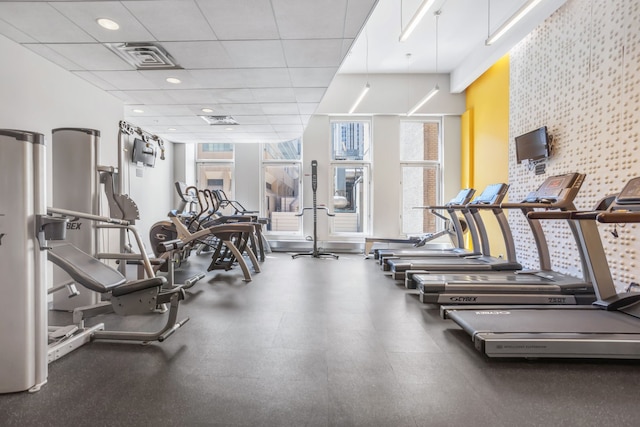 gym featuring visible vents, an accent wall, and a paneled ceiling