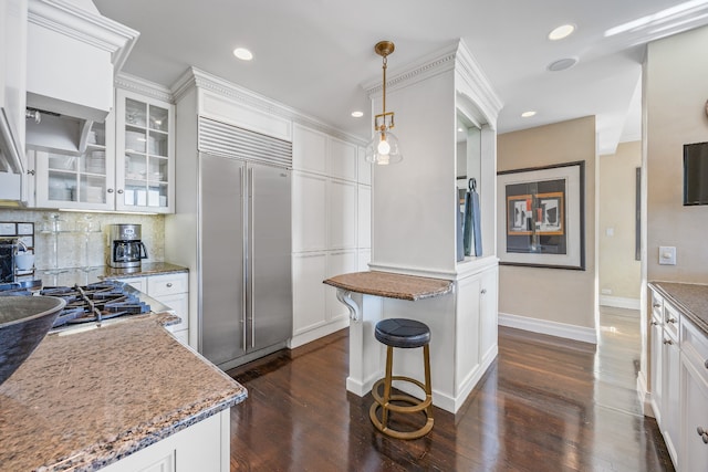 kitchen featuring tasteful backsplash, glass insert cabinets, dark wood-type flooring, stainless steel built in refrigerator, and white cabinetry