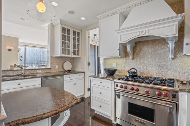 kitchen featuring premium range hood, a sink, white cabinets, appliances with stainless steel finishes, and glass insert cabinets