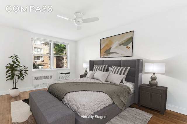 bedroom featuring ceiling fan, wood-type flooring, radiator, and an AC wall unit