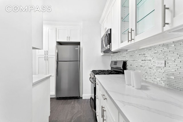 kitchen with light stone counters, stainless steel appliances, decorative backsplash, and white cabinets