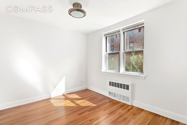 spare room featuring radiator and wood-type flooring