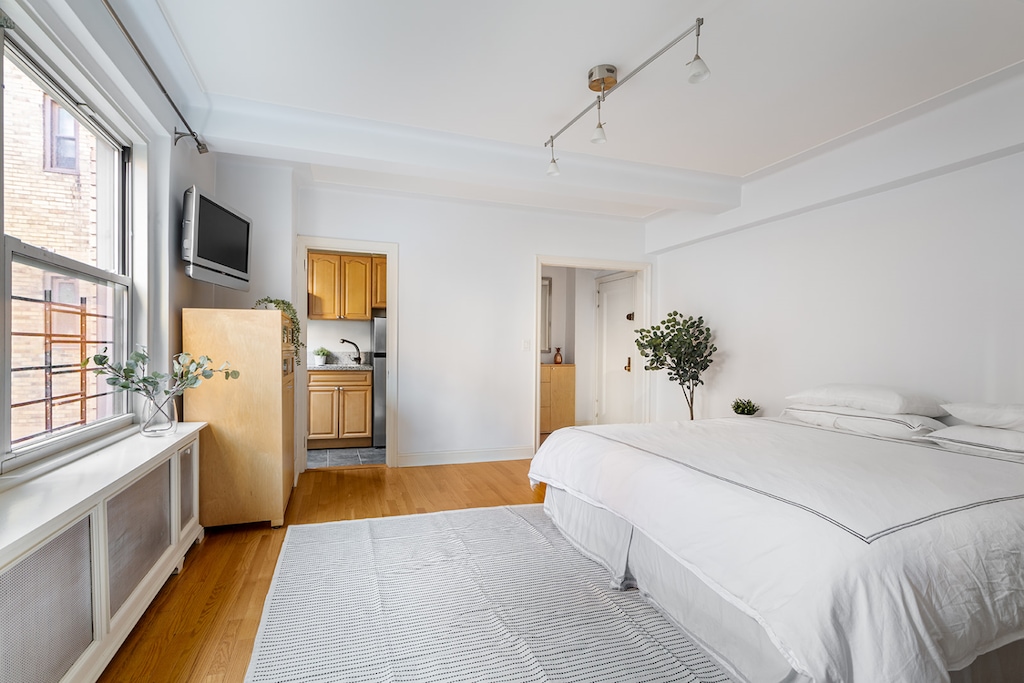 bedroom featuring freestanding refrigerator, rail lighting, a sink, and light wood-style floors
