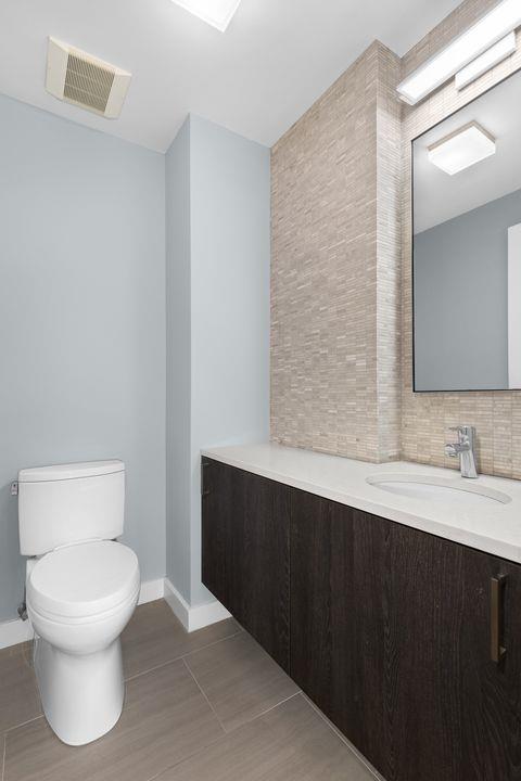 bathroom featuring visible vents, toilet, decorative backsplash, baseboards, and vanity