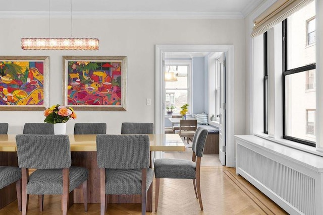 dining area featuring light wood finished floors, radiator heating unit, and crown molding