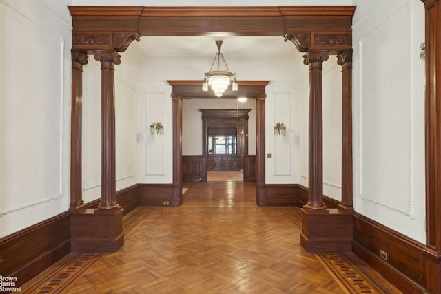 hallway featuring ornamental molding, dark parquet floors, and decorative columns