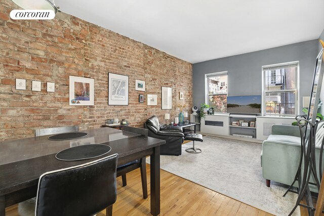 living room with brick wall and wood-type flooring