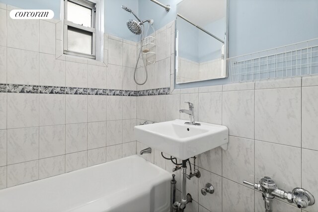 bathroom featuring tiled shower / bath, sink, and tile walls