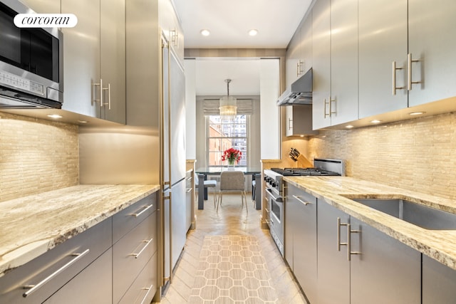 kitchen with light stone counters, stainless steel appliances, gray cabinets, and decorative backsplash