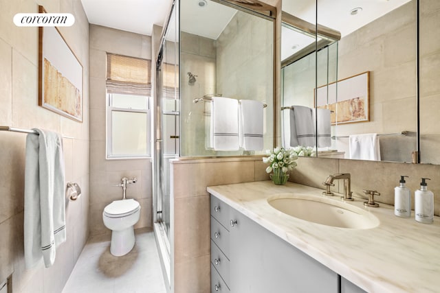 bathroom featuring toilet, a shower with shower door, tile walls, vanity, and tile patterned flooring