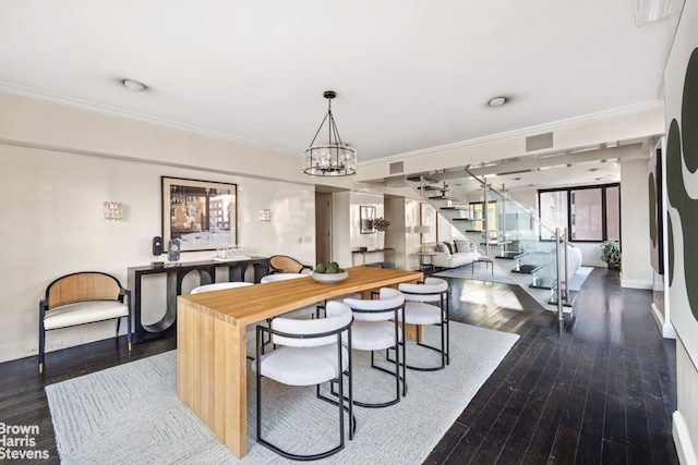 dining room featuring a notable chandelier, dark wood-type flooring, baseboards, stairway, and crown molding