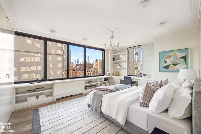 bedroom with crown molding, a city view, light wood-style flooring, and a notable chandelier