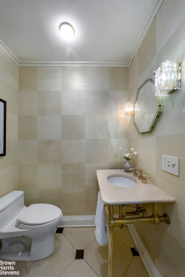 bathroom with crown molding, vanity, toilet, tile walls, and tile patterned floors