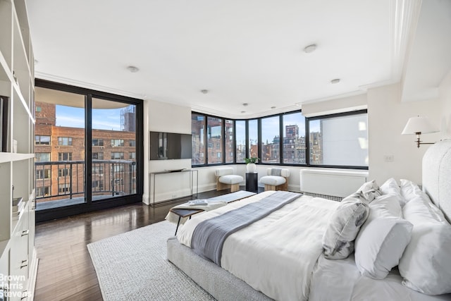 bedroom with access to exterior, multiple windows, a wall of windows, and wood finished floors