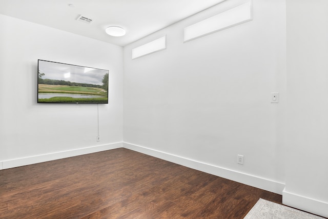 empty room featuring baseboards, visible vents, and dark wood finished floors