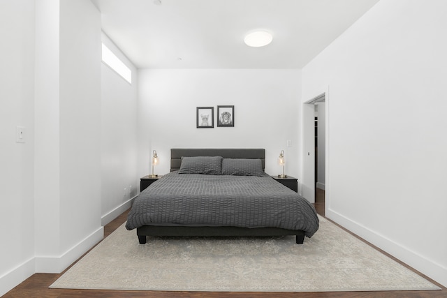 bedroom with dark wood-style flooring and baseboards