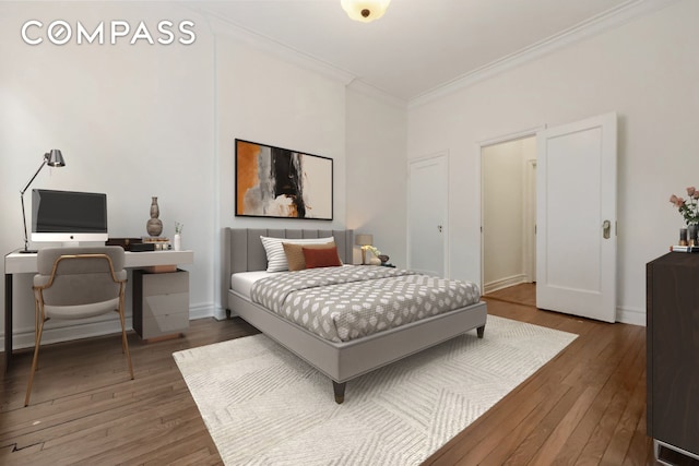 bedroom with baseboards, wood finished floors, and crown molding