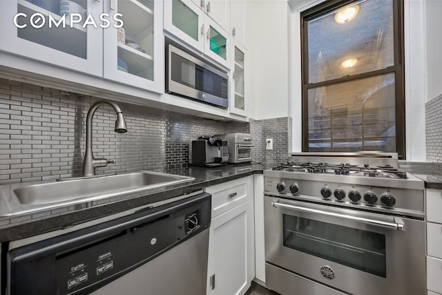 kitchen with decorative backsplash, white cabinetry, stainless steel appliances, and a sink