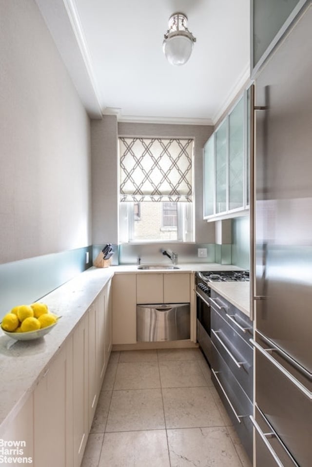 kitchen with a sink, high end appliances, ornamental molding, and light tile patterned floors